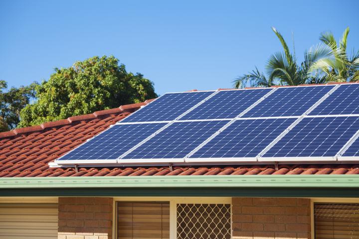 A photo of a house roof with solar panels on top.
