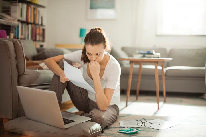 Woman sitting on the floor looking at a bill