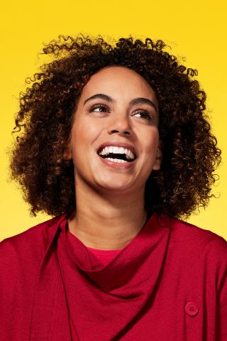 An image showing a young woman looking happy and looking off to something off-camera.