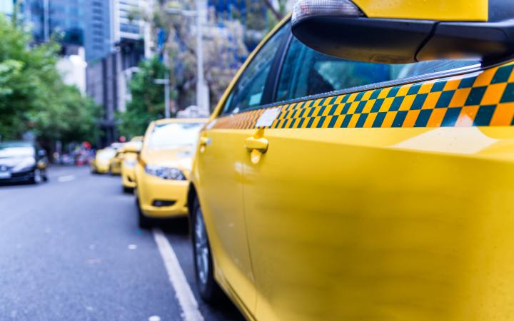 Image of a taxi sitting in a taxi rank in a metropolitan street