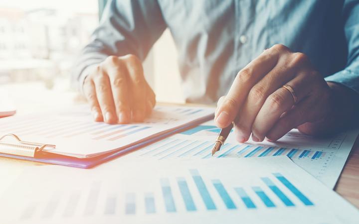 Photo of a person looking at paperwork, holding a pen