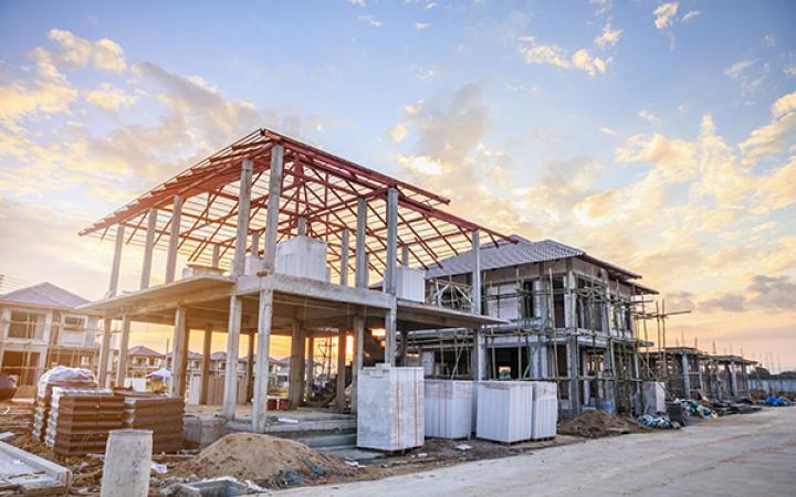 A photo of a house frame during construction, with sunset in the background