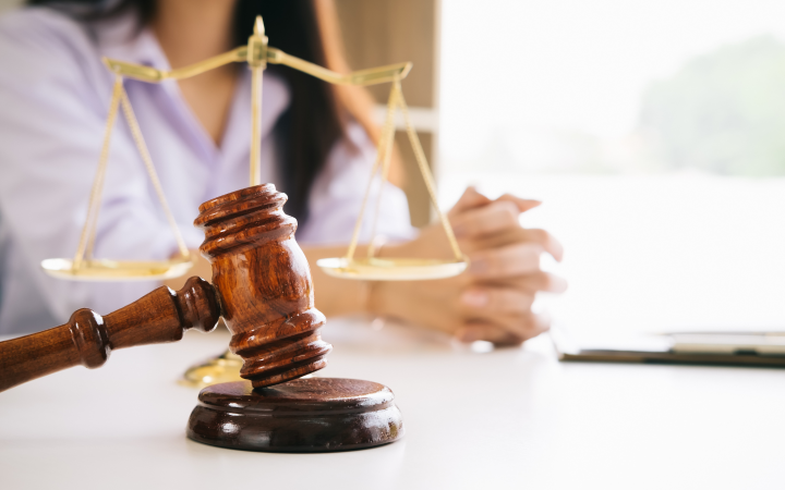 A gavel and justice scale at the front with a woman in the background.