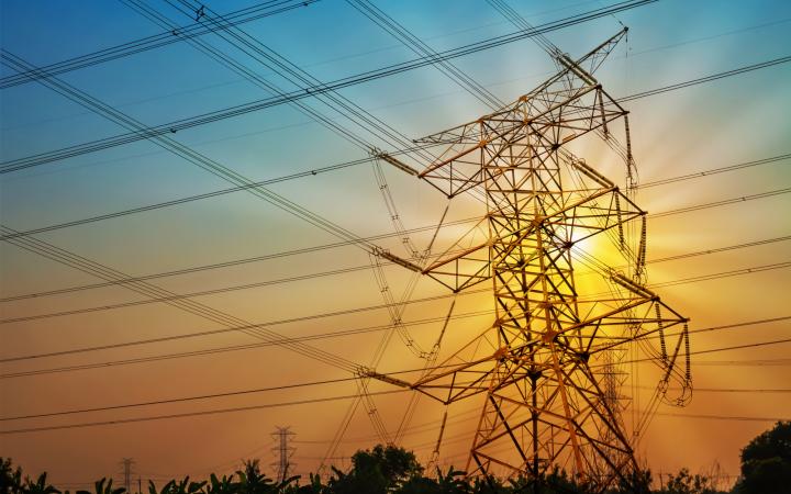 An image showing a transmission tower backlit by the sun.