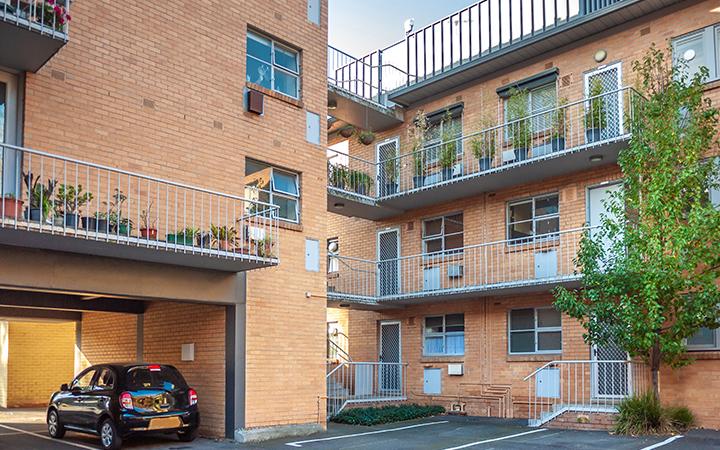 Three-storey apartment block with car park in the foreground