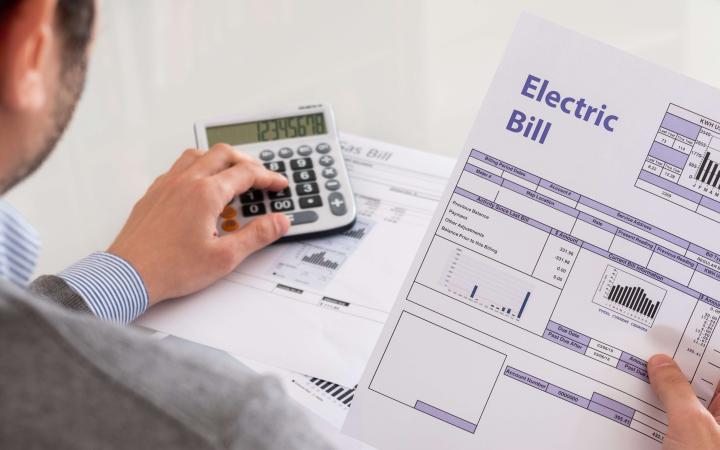 A man looking at an electricity bill, while using a calculator.