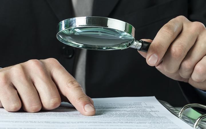 A person looking over records with magnifying glass
