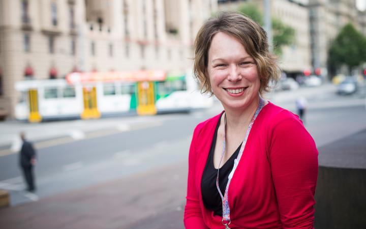 Image showing Lucy, Project Manager (Customer Engagement) at the Essential Services Commission, on a busy city street with a tram in the background.