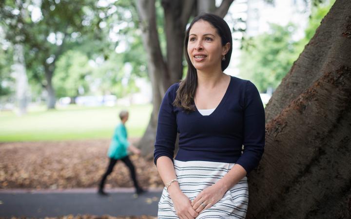An image of Cristina, water team member at the commission, leaning against a tree in a Melbourne park and smiling at something off camera.