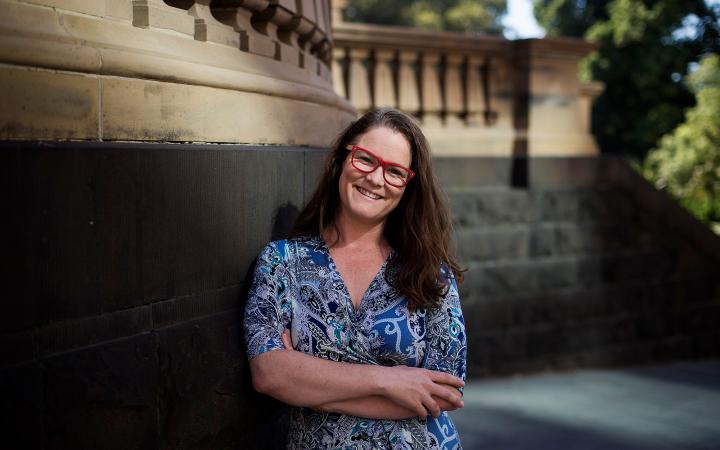 An image of Shannon, strategic communication team member, outside leaning against a building and smiling at the camera.