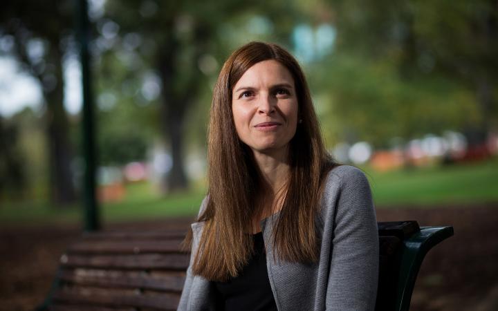 A photo showing Kate Symons, Commissioner at the Essential Services Commission, in a garden smiling at something off camera.