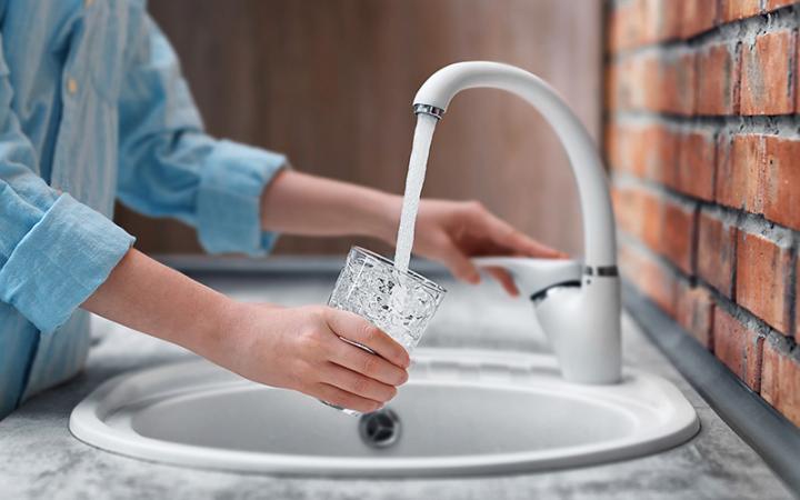 Glass of water being filled at a sink